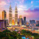 Kuala Lumpur skyline at sunset featuring the illuminated Petronas Twin Towers and surrounding cityscape at dusk